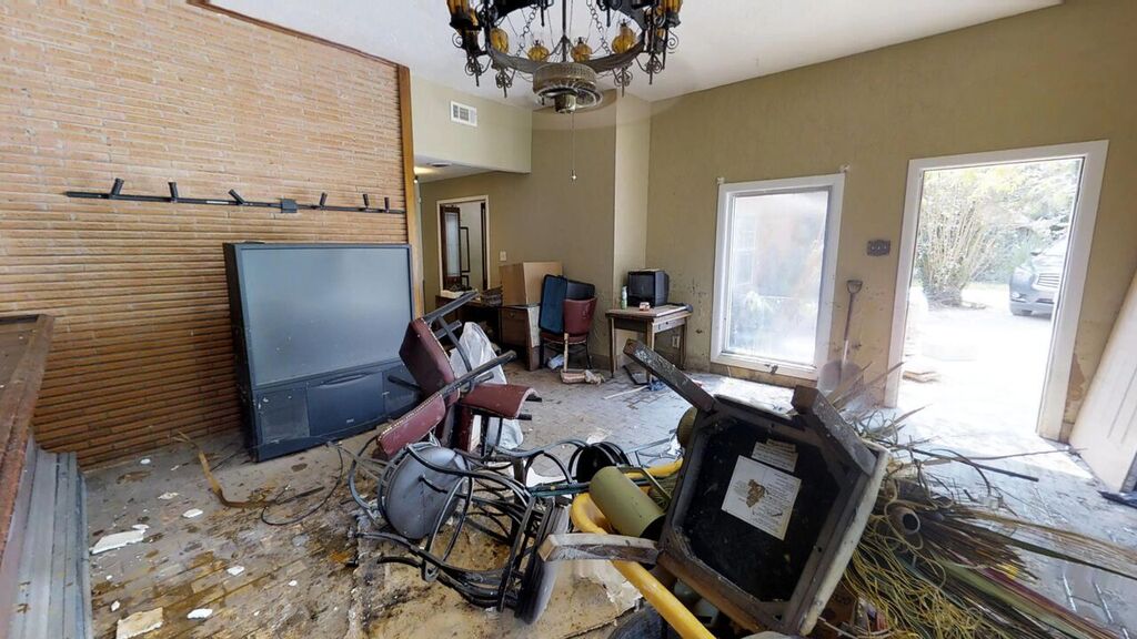 A living room with furniture and debris on the floor.