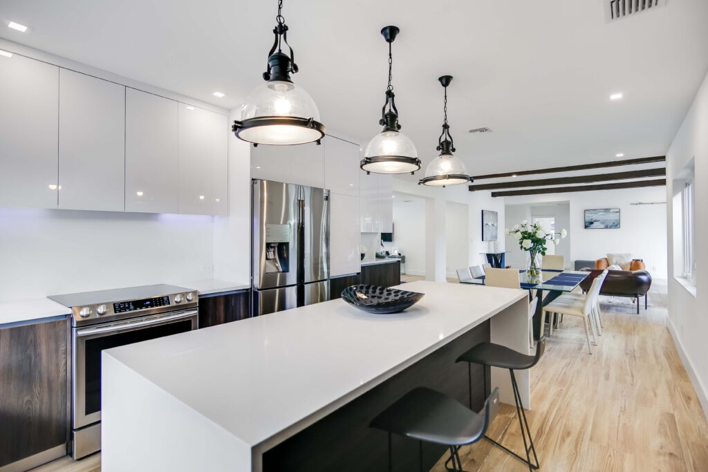 A kitchen with white counters and black chairs