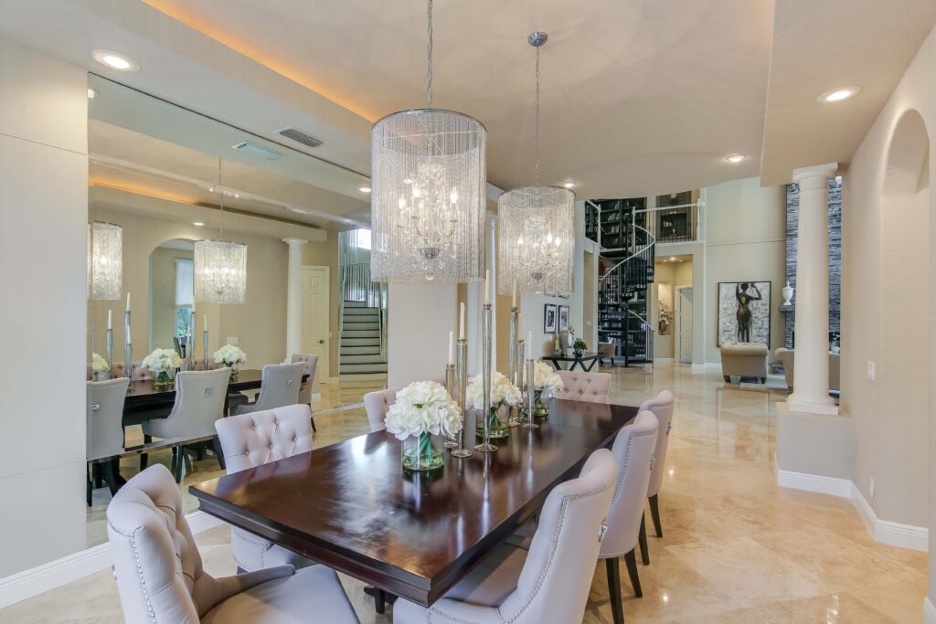 A dining room with a table and chairs, chandelier and marble floors.