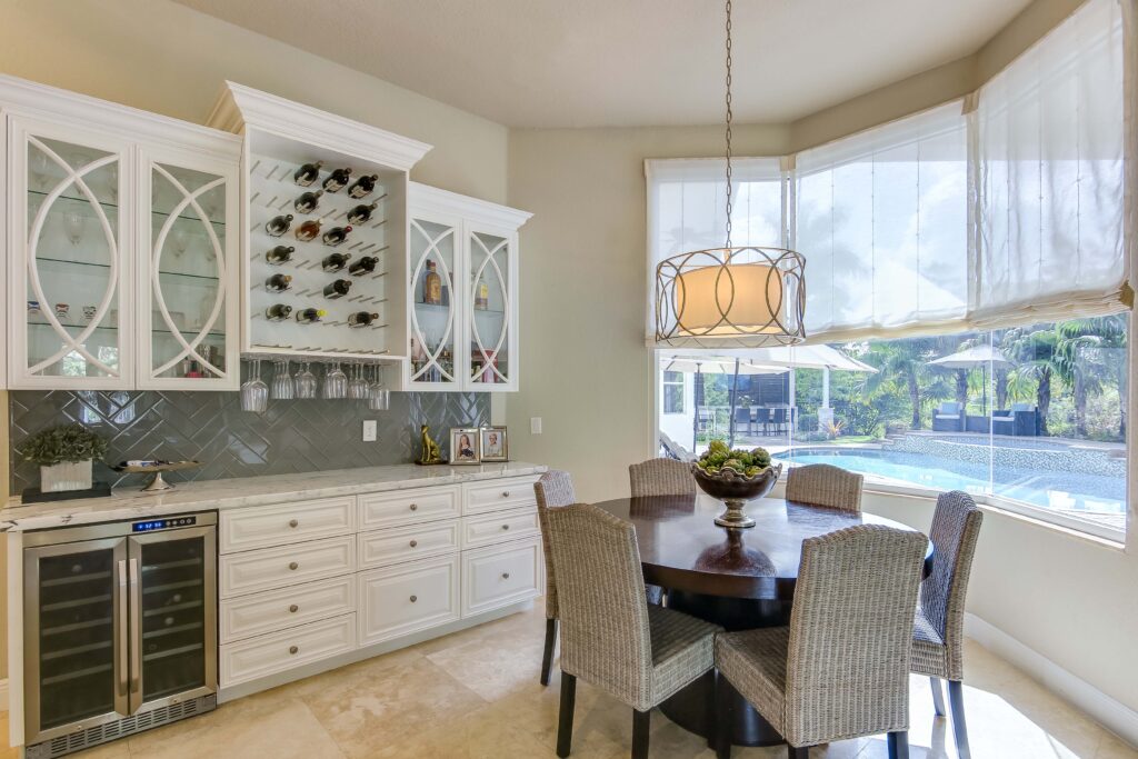 A dining room with a table and chairs, wine rack and cabinets.